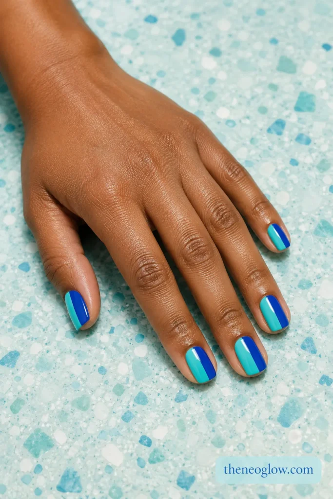 Short square nails divided vertically into glossy aqua and cobalt blue blocks on rich brown skin.