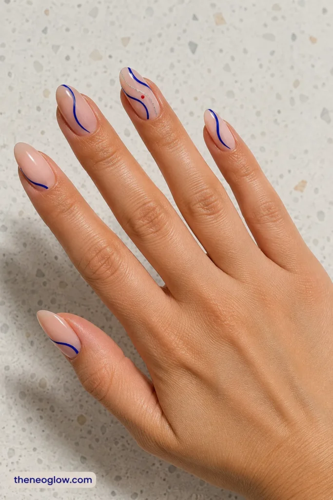 Medium almond translucent nails with loose cobalt swirls, a fine silver line, and one tiny red dot.