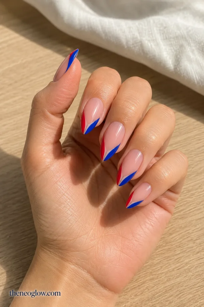 Medium almond nails with narrow navy tips and delicate red and silver firework lines on two accent nails.