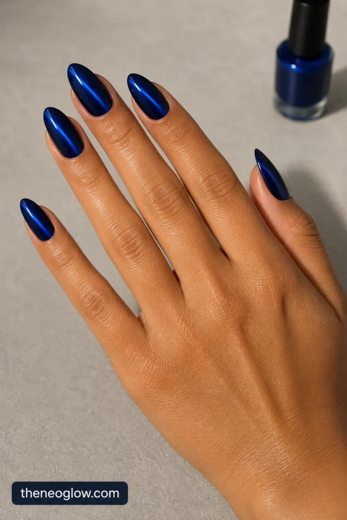 Medium almond sapphire cat-eye nails with narrow diagonal cobalt beams and dark edges on tan skin.