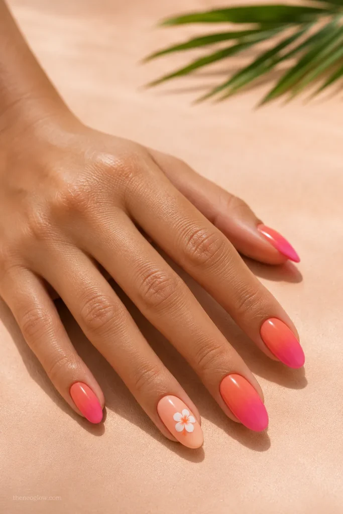 Coral-pink sunset ombré nails with a white tropical flower
