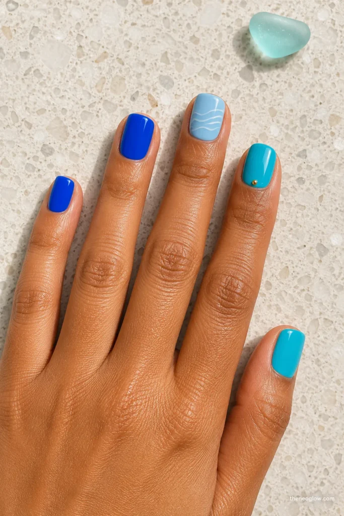 Short turquoise and cobalt nails with a white wave accent
