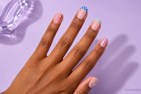 Medium-deep brown hand with glossy Y2K nail art featuring checkerboard French tips, pink swirls, aqua tips, chrome, and a silver star.