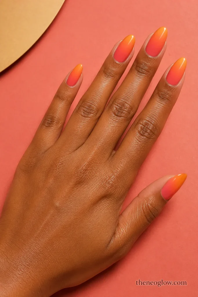 Medium almond nails fading smoothly from warm coral at the cuticles to glossy tangerine tips.