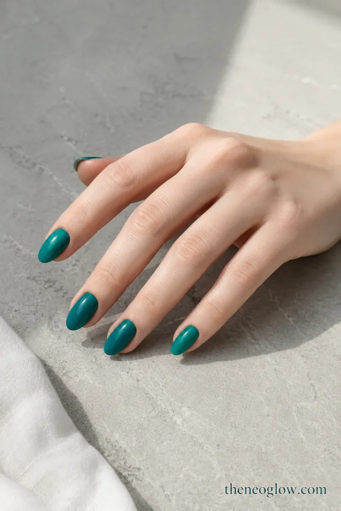 Saturated Mediterranean teal cream polish on medium almond nails with a glossy finish on fair cool-toned skin.