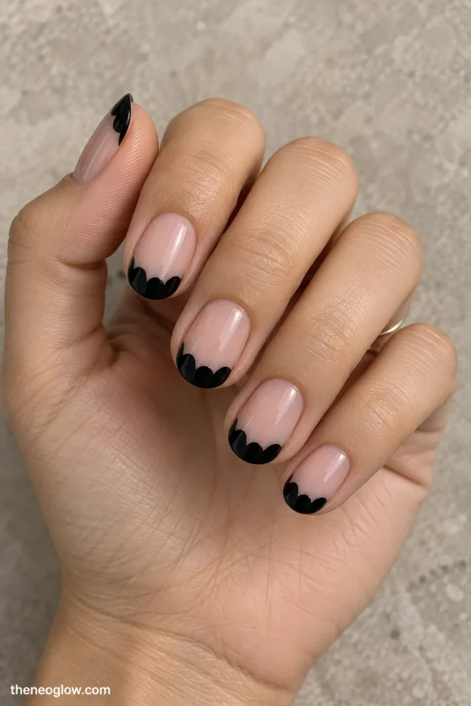 Sheer press-on nails with black bat-wing-shaped French tips worn on one hand. halloween french tip nails