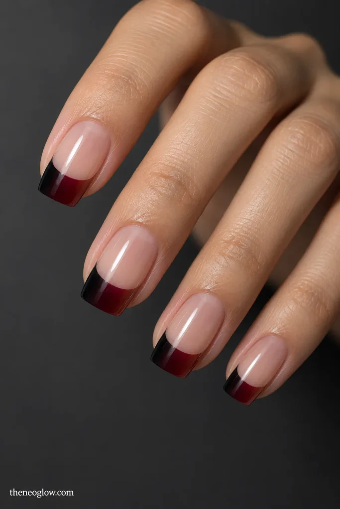 Sheer nails with black-to-oxblood color blended across the French tip band.
