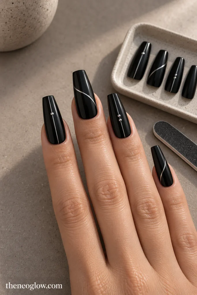 Long black coffin press-ons with flat silver details shown fitted sidewall to sidewall beside matching tips. gothic coffin nails