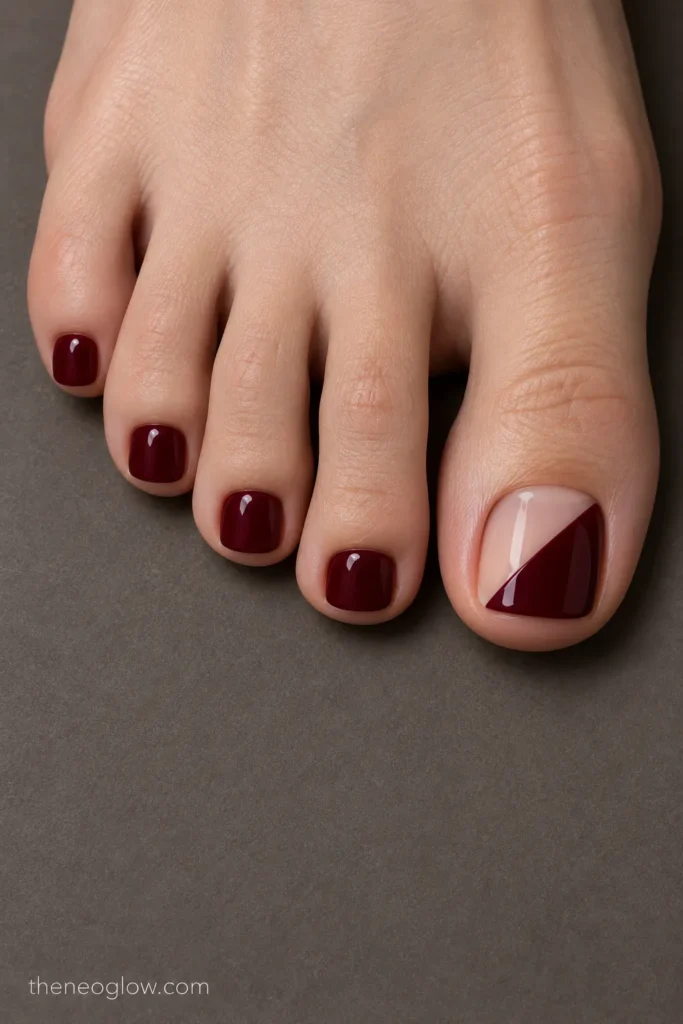Big toenail divided diagonally between opaque burgundy and sheer neutral with solid wine smaller toes.