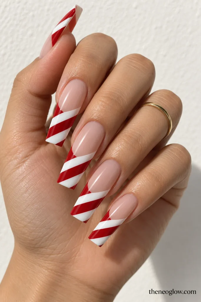 Long coffin nails with sheer bases and diagonal red-and-white candy-cane tip bands.