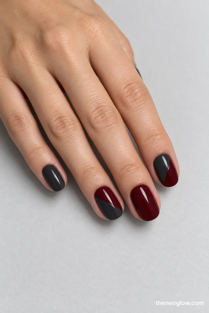 Charcoal and dark-wine nails with two clean diagonal color-block accents.