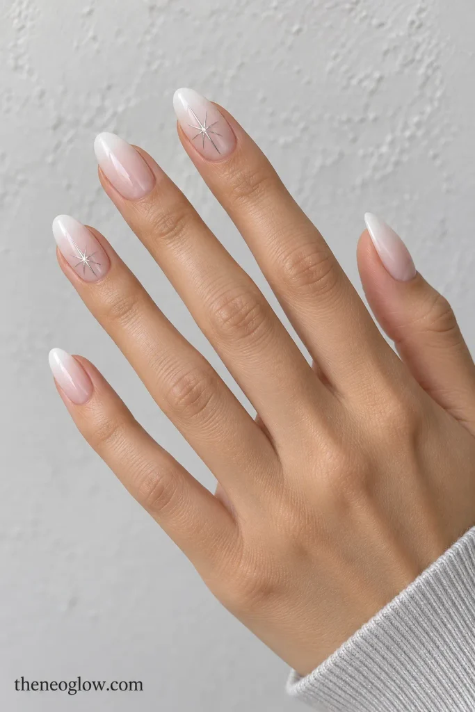 Medium almond milky ombré nails with thin off-center silver starbursts. christmas nail ideas