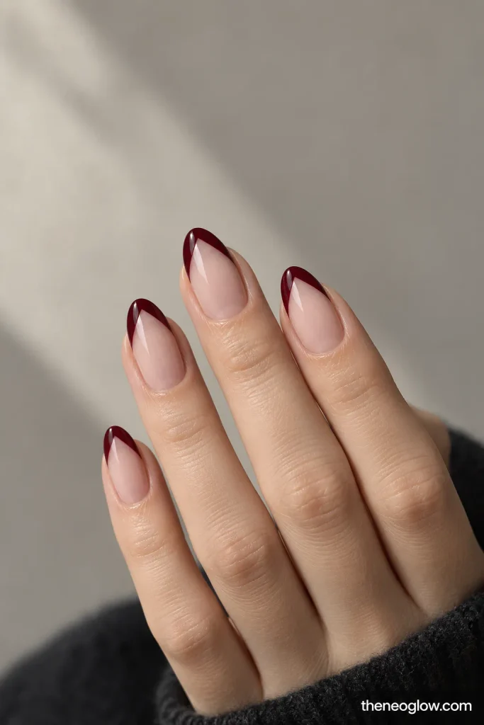 Sheer nails with narrow oxblood V-tips and open negative-space centers.