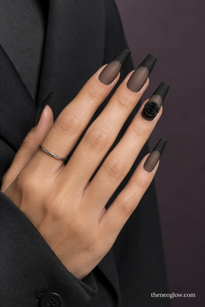 Long coffin acrylic nails with sheer black bases, matte black tips, and one sculpted black rose.