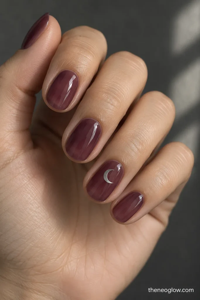 Translucent smoky plum nails with a small silver crescent on the ring finger.