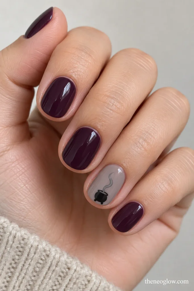Deep plum short round nails with a tiny black cauldron accent and a soft gray smoke curl.