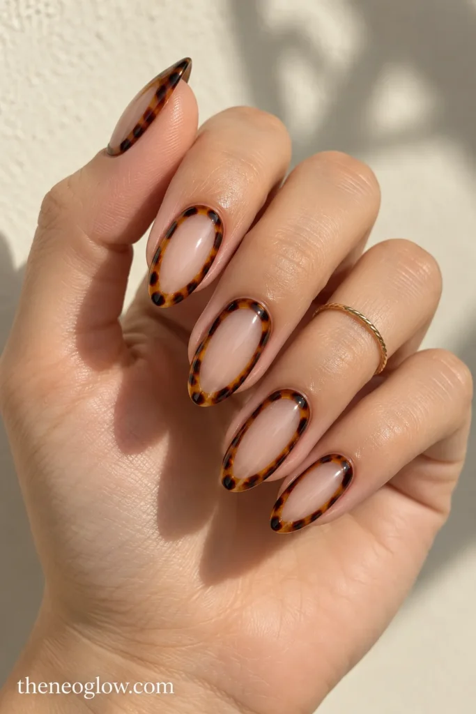 Medium almond nails with thin tortoiseshell perimeter frames surrounding sheer centers.