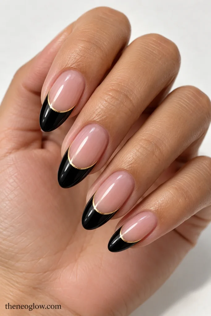 Medium almond French tips in glossy black with fine warm-gold lines below the curved edges.