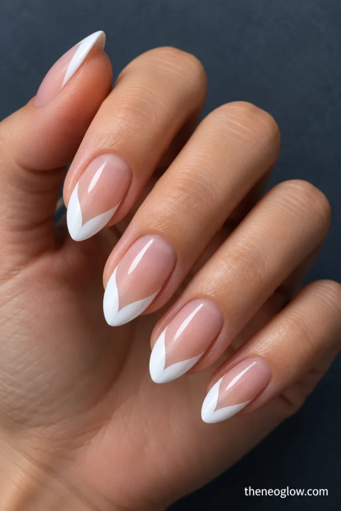 Medium almond nails with symmetrical opaque-white V-shaped French wings over a sheer beige-pink base.
