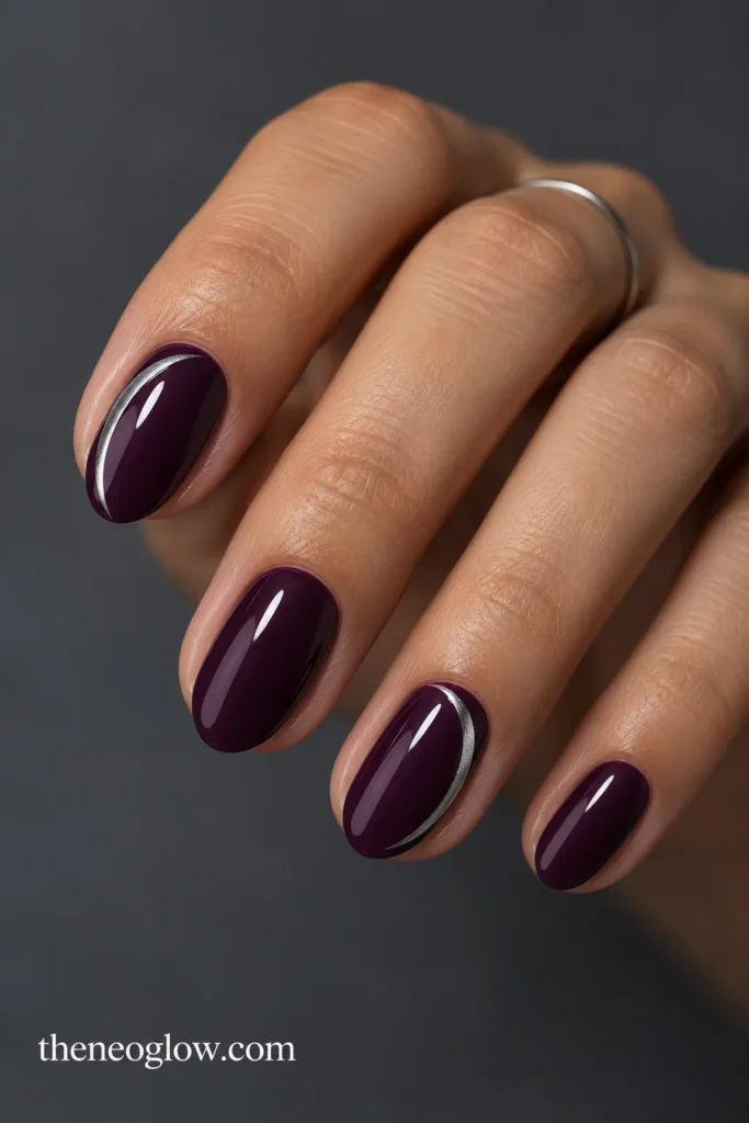 Deep-aubergine genuinely short almond nails with slim C-shaped silver side arcs on the index and ring fingers. short winter nails