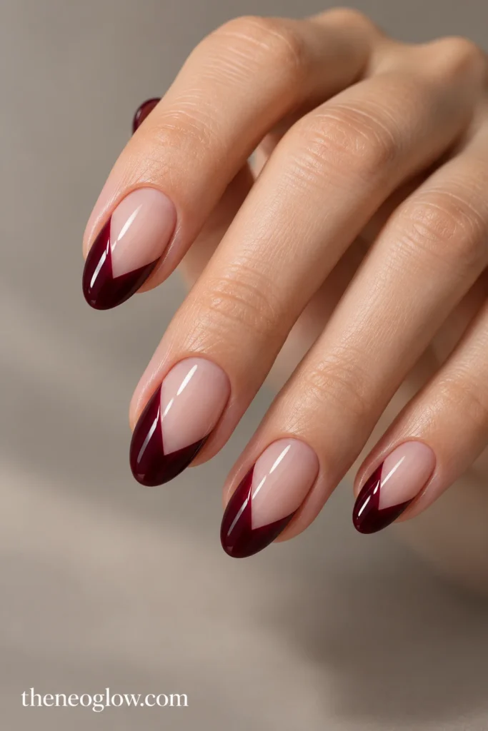 Medium almond nails with glossy black-cherry French tips meeting at off-center V points.