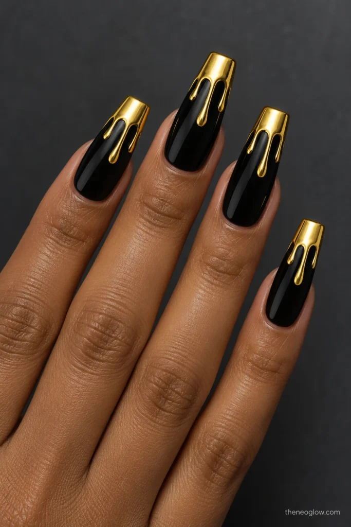 Long glossy black coffin nails with mirror-gold tip caps and two flat rounded gold drips on each nail. black and gold nails