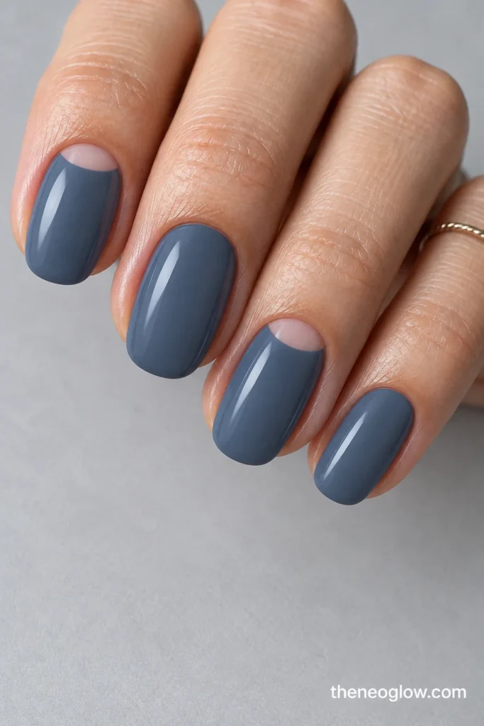 Medium oval blue-slate nails with bare semicircle cuticle windows on index and ring fingers.