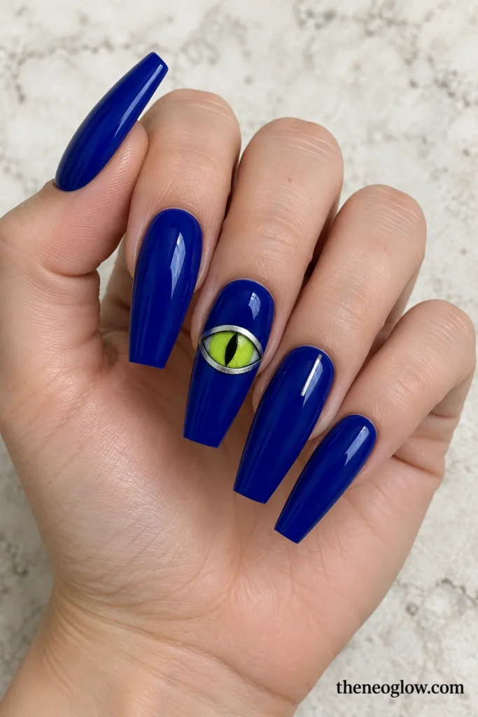 Glossy midnight-cobalt coffin acrylics with a silver-outlined monster eye and chartreuse iris.