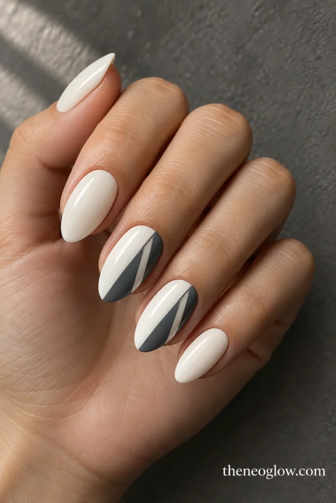 Cool-cream almond nails with steel-gray trapezoid window accents on two fingers.