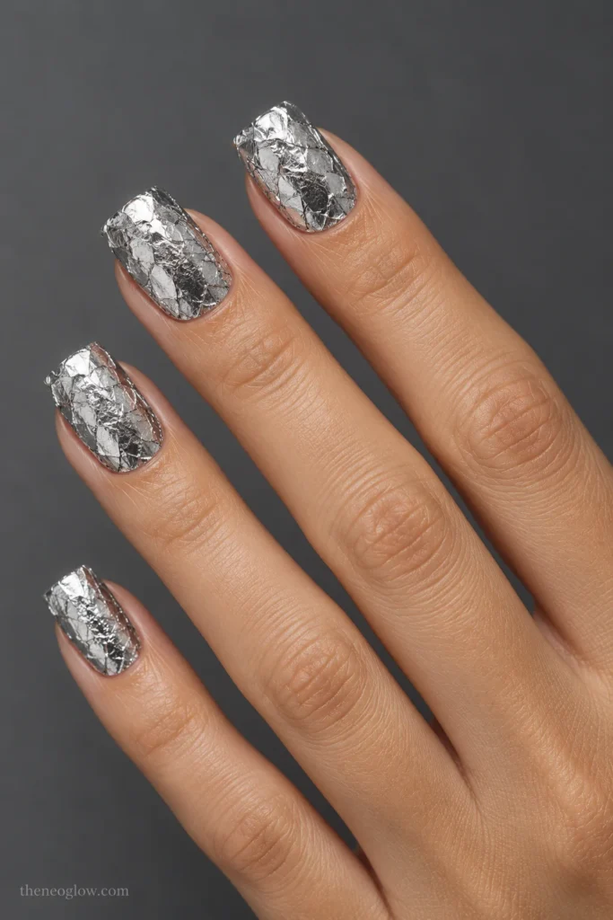 Medium square nails with overlapping crinkled silver foil fragments beneath a smooth glossy topcoat.