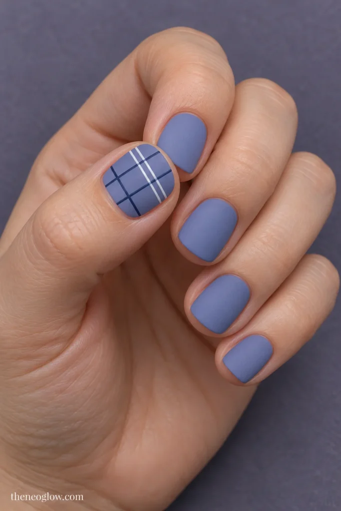 Matte dusty-periwinkle short squoval nails with a compact white-and-navy windowpane plaid on the thumbnail.