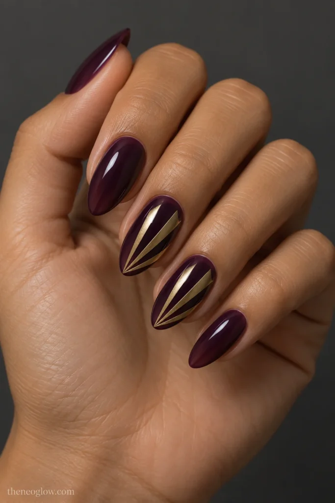 Medium almond fig-purple jelly nails with three brushed-brass fan blades on the middle and ring fingers.