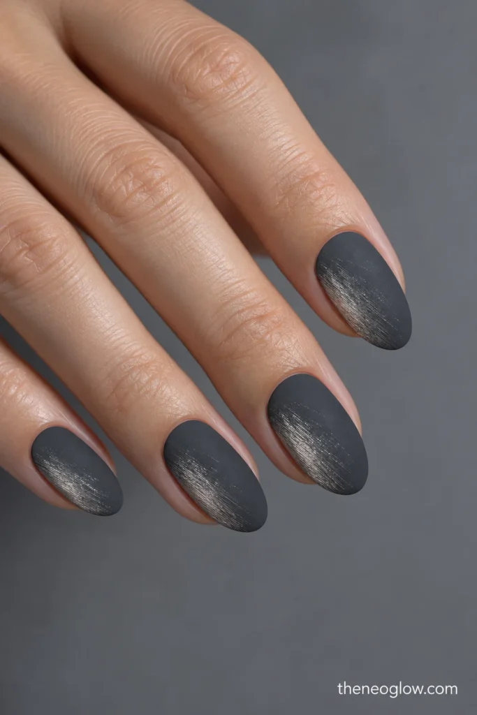 Medium matte graphite almond nails with diagonal brushed-pewter pigment.