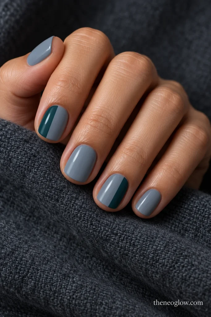 Short gray-blue squoval nails with opaque deep-teal outer side panels on the index and ring fingers.