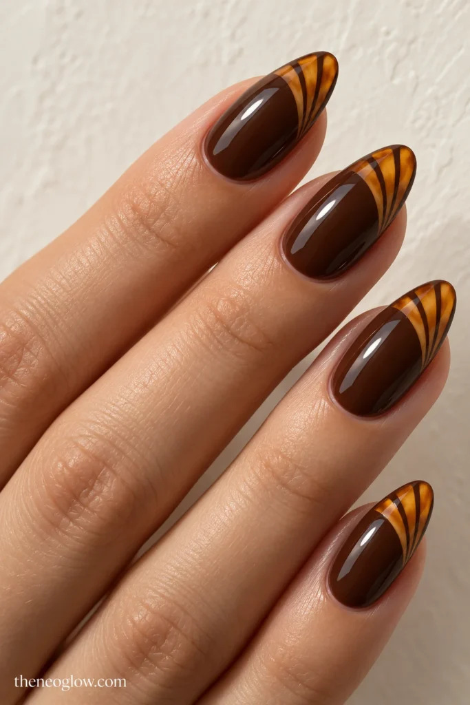 Glossy chestnut almond nails with three amber fan-shaped blades across each tip.