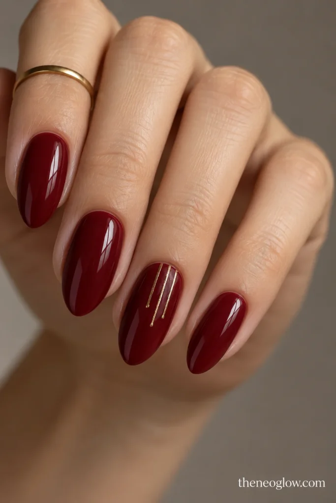 Deep garnet almond nails with fine bronze fringe lines descending from the tips of accent nails.