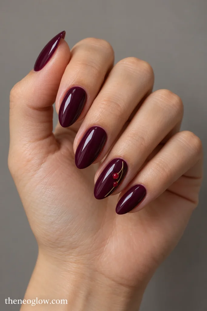 Glossy mulberry almond nails with fine golden stems and tiny red berries on the ring fingers.