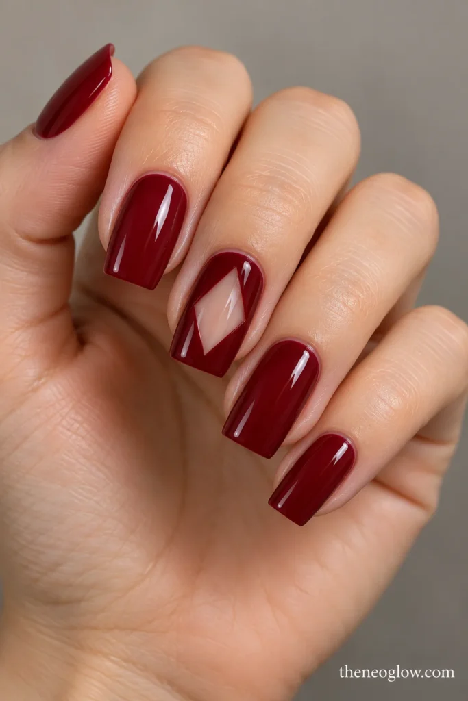 Glossy wine-red tapered-square nails with a central transparent diamond on the middle fingernail.
