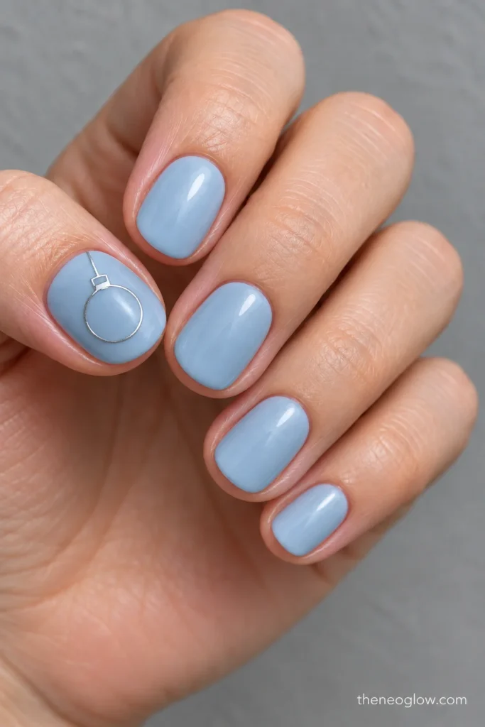Short misty-blue oval nails with a delicate silver ornament outline on the thumb and subtle pearly finishes on the smaller nails.