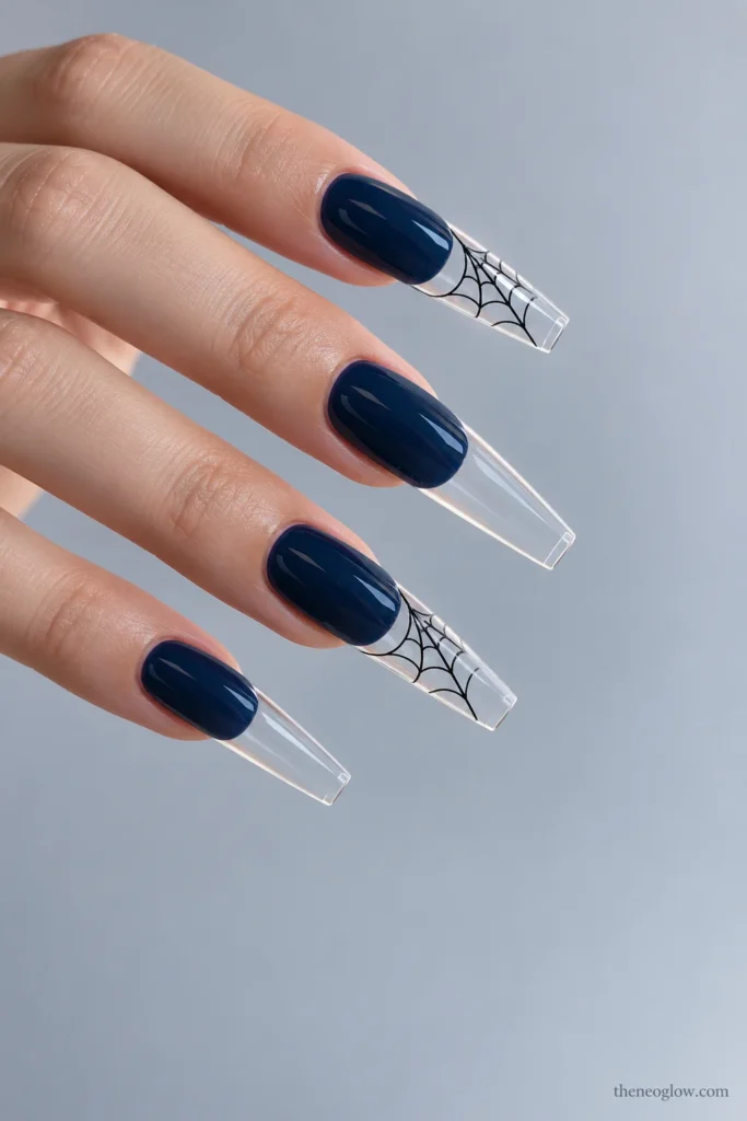 Long coffin acrylic nails with opaque ink-blue beds and transparent free-edge tips containing black spiderwebs.
