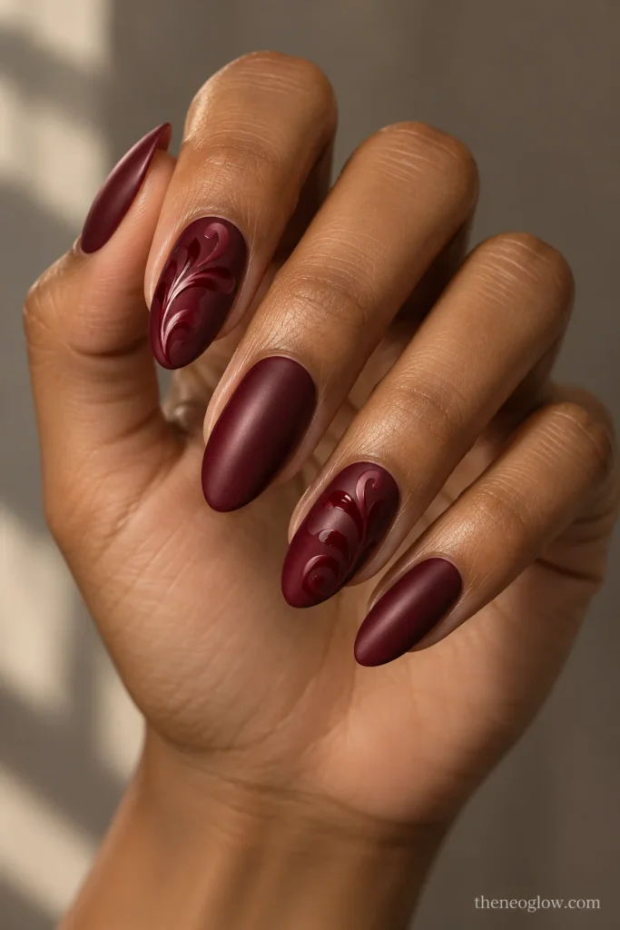 Medium merlot satin almond nails with curling tone-on-tone glossy damask flourishes on two accents.