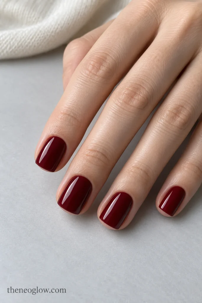 Short square nails painted opaque cool garnet-red cream with a smooth high-gloss finish.