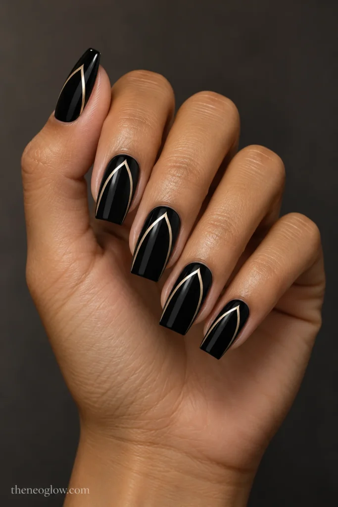 Glossy onyx-black tapered-square nails with narrow champagne-gold pointed arch outlines on every nail.