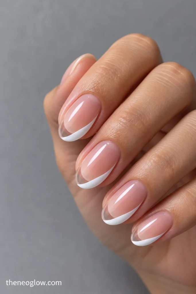 Medium oval nails with one-sided curved white French tips tapering toward a partially clear free edge.