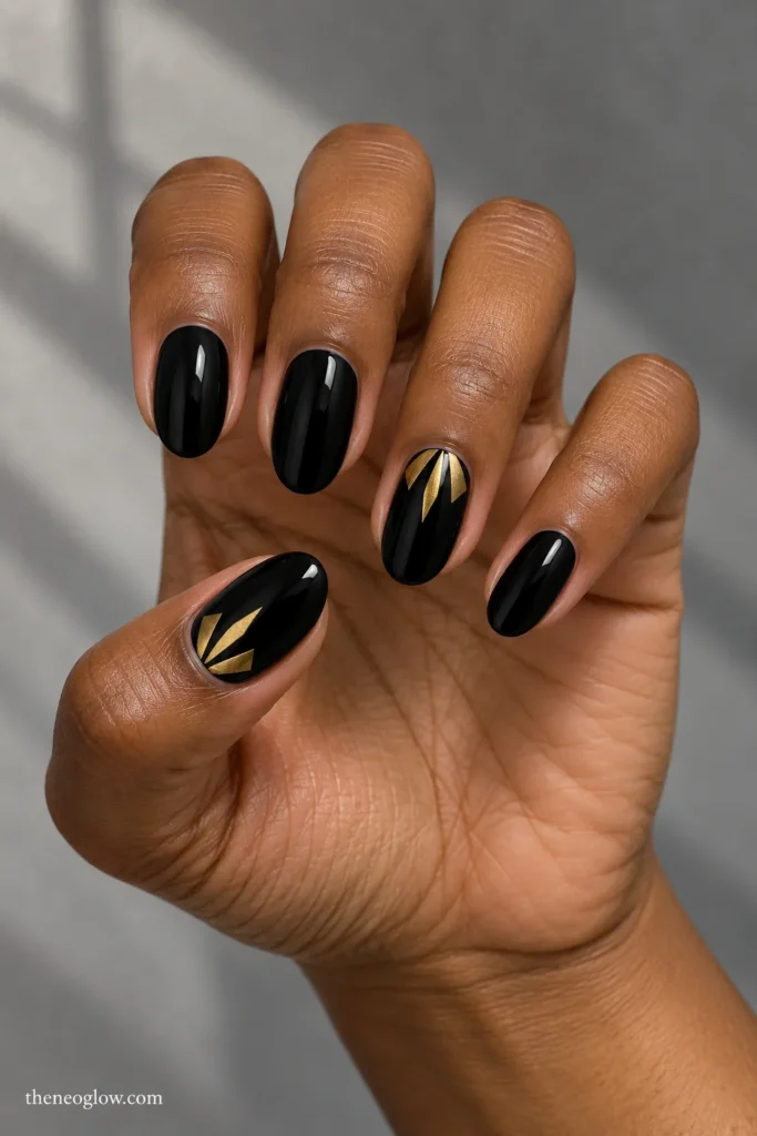 Medium oval black nails with three antique-gold fan blades at the thumb and ring-finger cuticles.