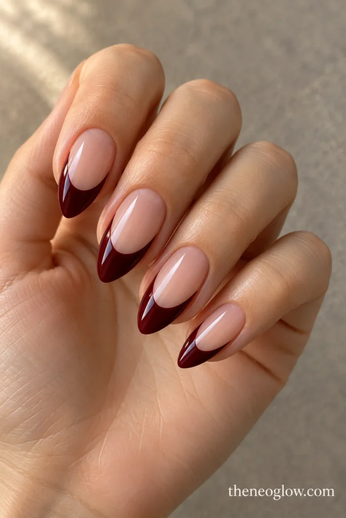 Medium almond nails with deep glossy oxblood French tips and tall sheer centers.