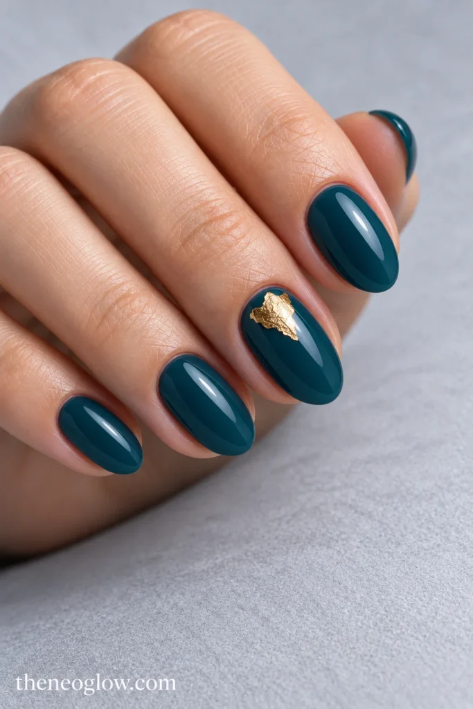 Glossy petrol-teal short almond acrylics with one flat gold-foil accent near the ring-finger cuticle.