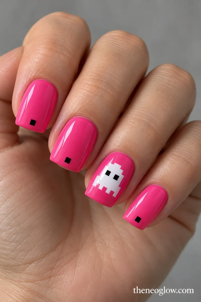 Short bubblegum-pink acrylic nails with a white pixel ghost and tiny black square accents.