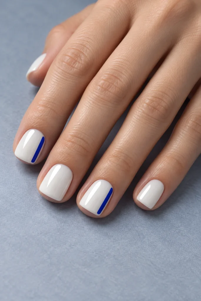 Very short porcelain-white square acrylic nails with narrow cobalt side bars on the index and ring nails.