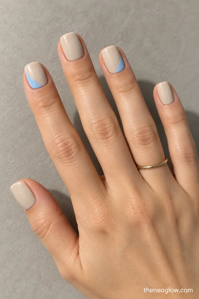 Short stone-beige soft-square nails with powder-blue corner triangles on index and ring fingers.